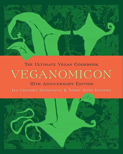 Cover for the book Veganomicon, dark green background with a light green V with an orange banner across the cover with the title over top