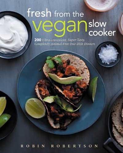 A cover for the book Fresh from the Vegan Slow Cooker. Features a mostly blue background with a plate of tacos and bowls of limes and sour cream sitting near it.