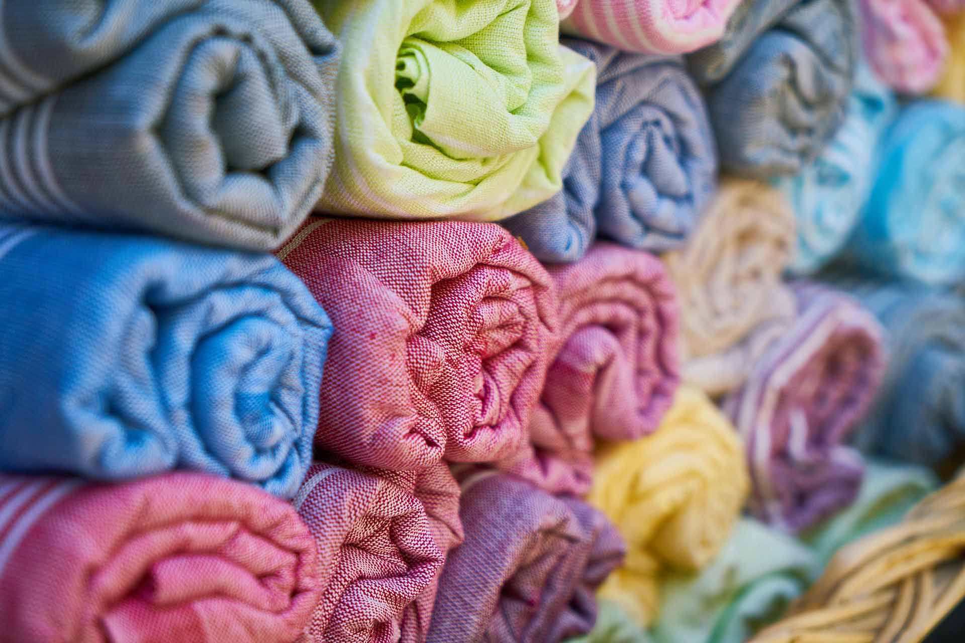 A bunch of colorful fabrics rolled up and stacked on top of each other.