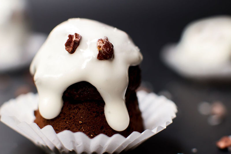 A closeup of a chocolate ghost with white frosting head sitting on top of a white wrapper.