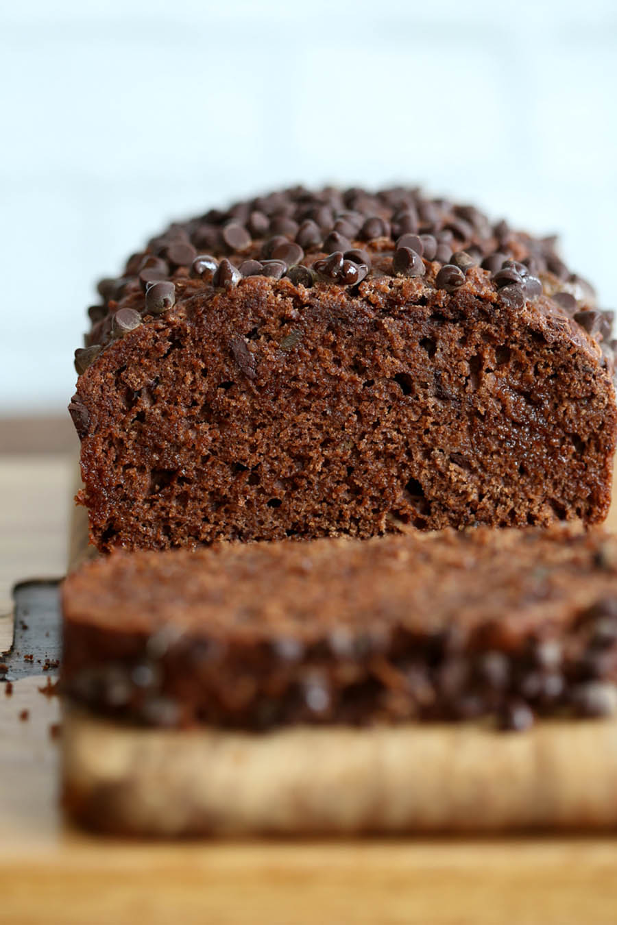 A close up of a loaf of chocolate gingerbread cake sliced open sitting on a wooden cutting board.
