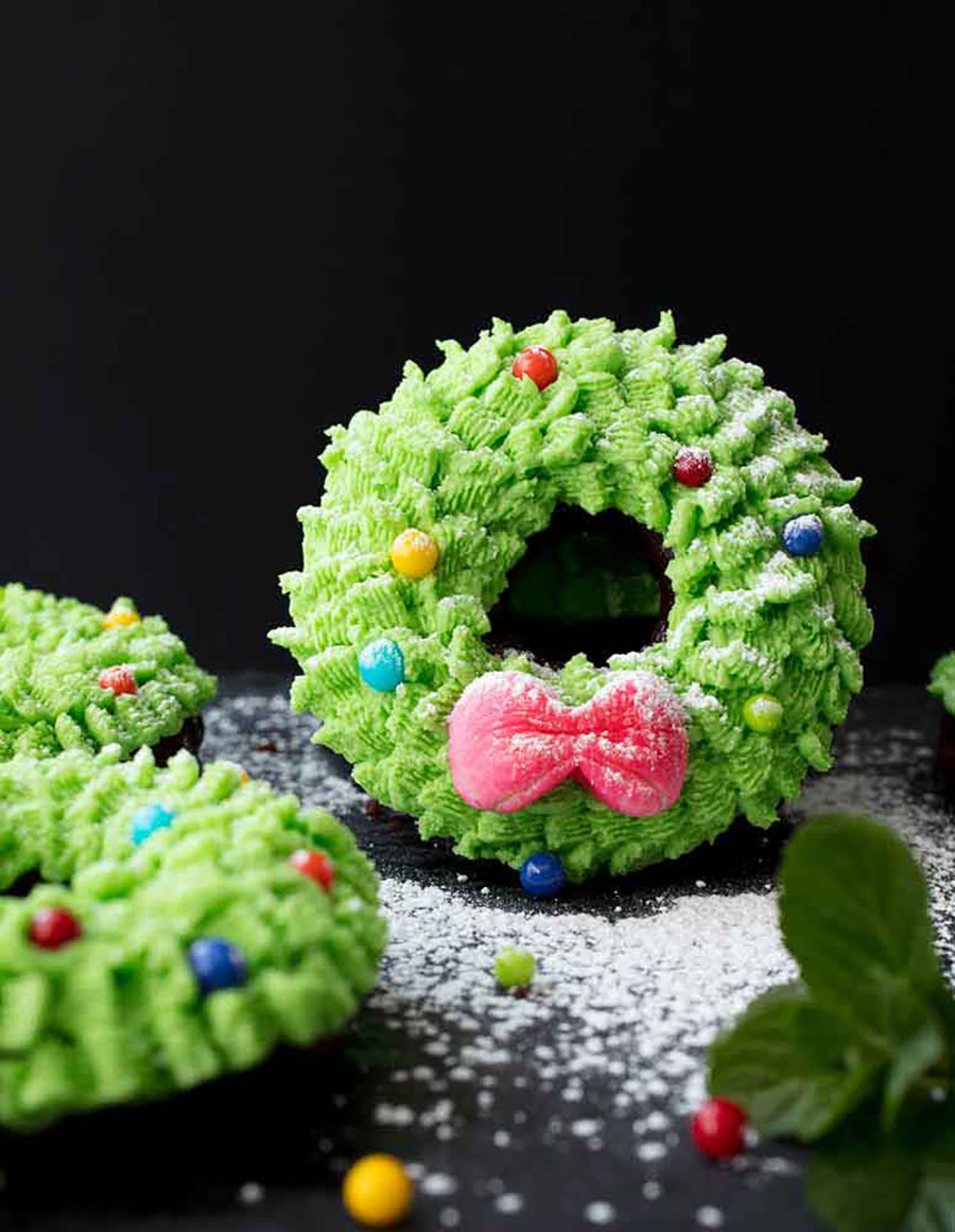 Several mini wreath cakes sitting on a black table with a black background.