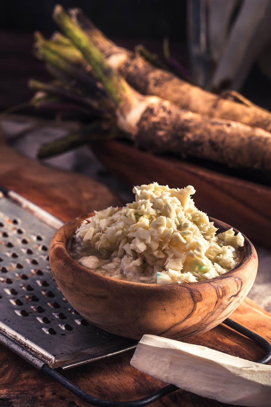 Wooden bowl of coarsely grated horseradish on table