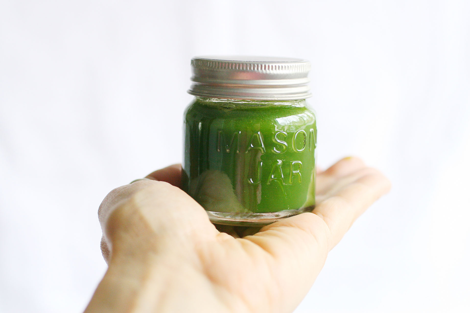 A jar of green food coloring sitting on an outstretched palm.