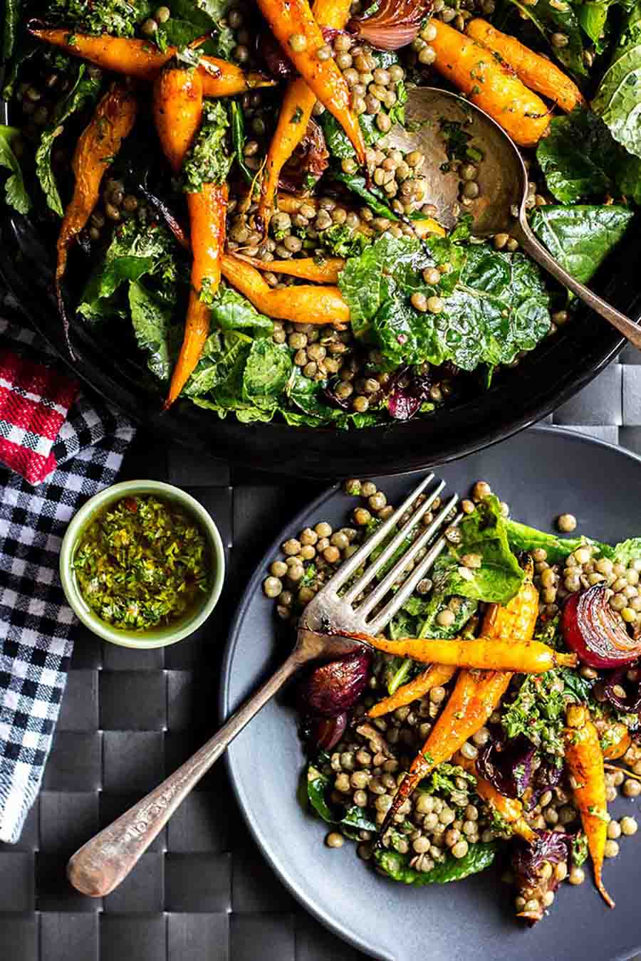 Lentil salad with roasted vegetables sitting in a serving dish with a single serving portion in front.