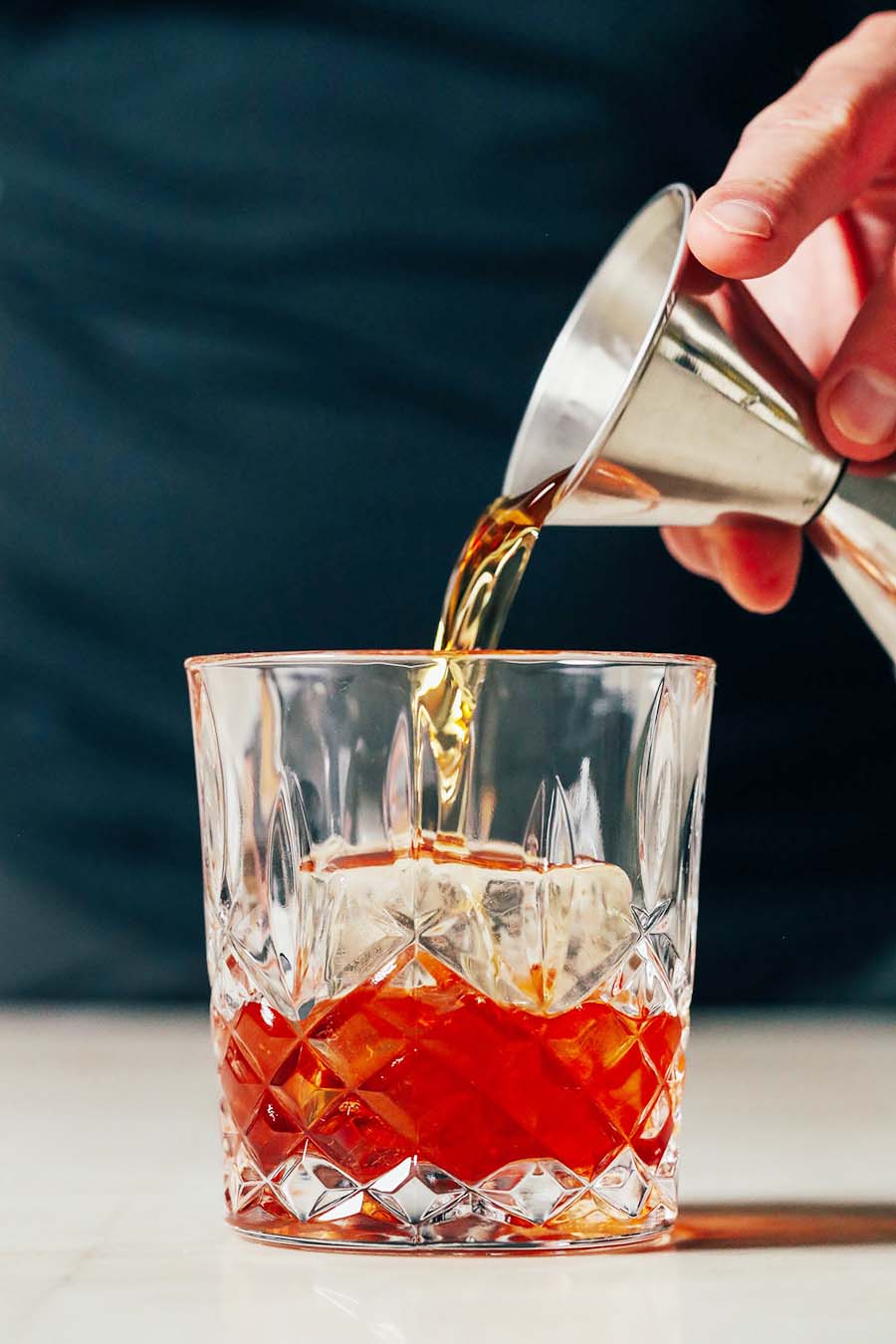 Someone pouring an Old Fashioned cocktail