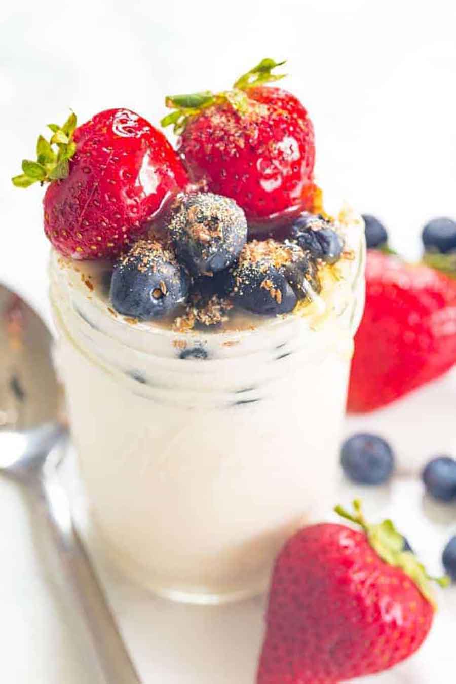 A glass of yogurt topped with fresh berries