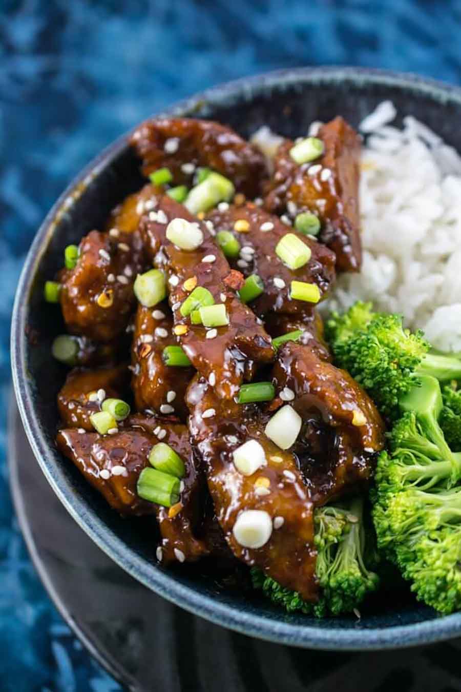Blue bowl of seitan "beef" served with white rice and broccoli