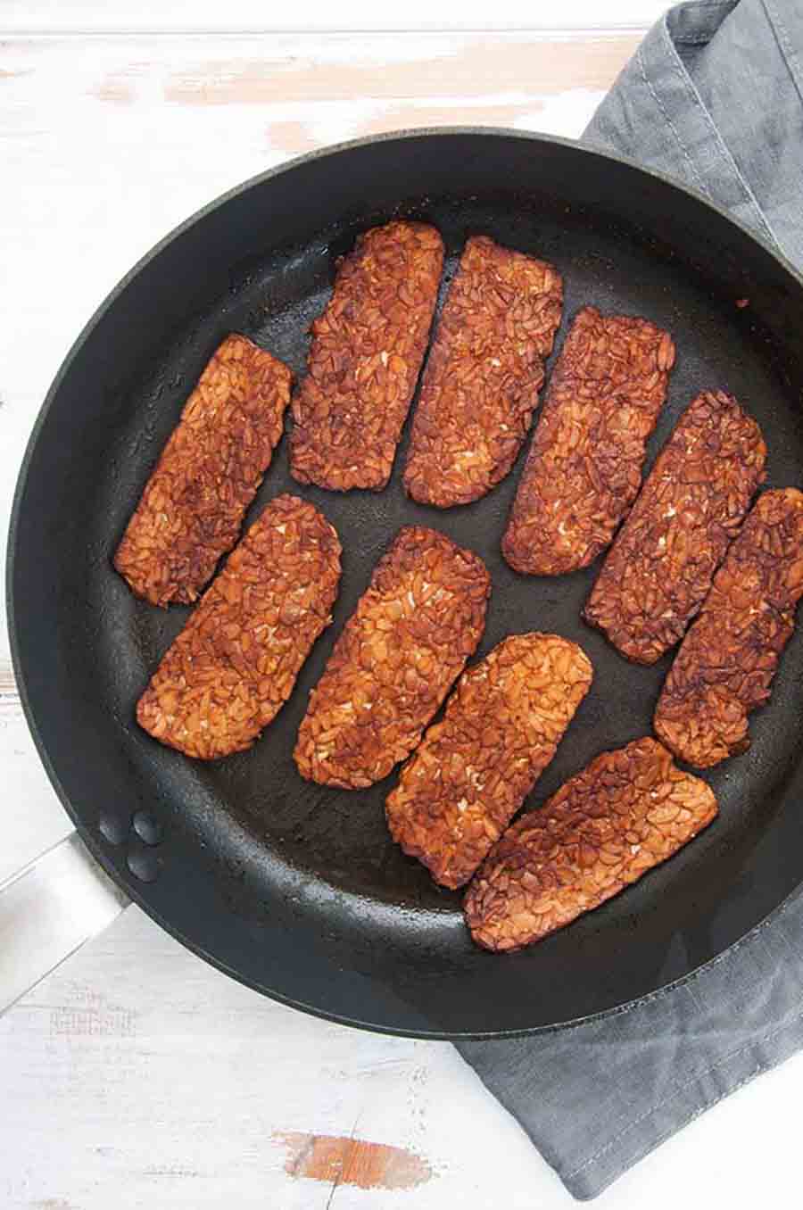 A black skillet of tempeh bacon